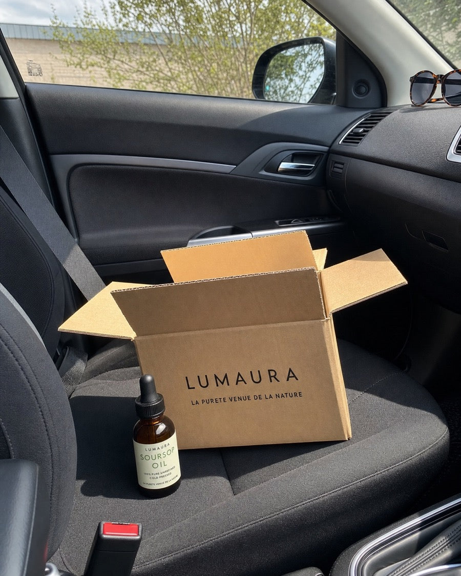 Bottle of Lumaura soursop oil held in natural daylight